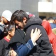 A man seen from the waist up cries as he hugs a woman