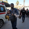 A man carries an injured child beside an ambulance in Gaza