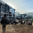 People stand in front of a burned-out hospital building