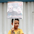 A boy holds a poster with a man and Arabic text on it 