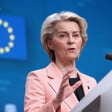 European Commission President Ursula von der Leyen stands at a podium against a blue background