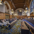 A wide angle view of an audience seated before a panel of judges in an ornately decorated courtroom