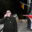 Dr. Abu Sitta speaks in a microphone outside a building with German and Palestinian flags visible behind