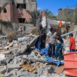 A man and three children stand on top of a pile of rubble