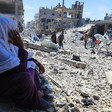 A woman is seated and is overlooking the rubble and debris around her 