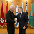 Gallant and Blinken shake hands while standing in front of Israeli military flags