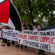 Protesters with a Palestinian flag and banners protesting against cooperation between France and Israel 
