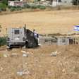 Israeli armored vehicles and Israeli flag in a field 
