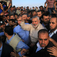 Ismail Haniyeh smiles and raises a fist in the middle of a crowd of men