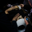 Hands hold the face of a dead man on a stretcher 