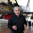 Israel's Prime Minister Benjamin Netanyahu stands in front of a warplane 