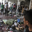 People stand around a room filled with ashen and blood-stained personal belongings