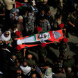 Aerial view of body wrapped in Palestine flag carried on stretcher in crowd