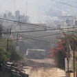 An armored vehicle is seen amid the dust on torn-up roads