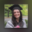 Young woman wearing graduation cap and a kuffiyeh around her shoulders smiles while looking toward camera