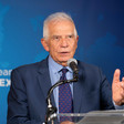 European Union Representative Josep Borrell stands in front of a microphone with a blue background behind him 