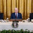 Kamala Harris, Joe Biden and Antony Blinken seated with flags behind them