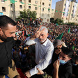 Yahya Sinwar smiles while giving the V for victory hand gesture with crowd of people behind him