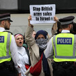 A protester holds up a sign saying Stop British Arms Sales to Israel as she stands behind police and beside other protesters
