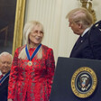 President Donald Trump at podium in East Room of White House with Miriam Adelson and Senator Orrin Hatch