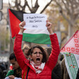 A woman holds aloft a sign calling to free Dr. Hussam Abu Safiya as other protesters join her