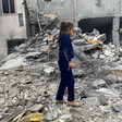 Two young children walk through the rubble of a destroyed house 