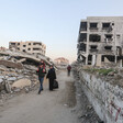 A family walks on a street between destroyed buildings