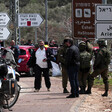 Israeli soldiers and settlers and police officers stand beside vehicles and a number of signposts in the occupied West Bank 