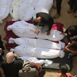 Overhead view of men and women sitting next to several shrouded bodies