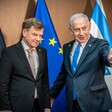 German Foreign Minister Johann Wadephul and Israeli Prime Minister Benjamin Netanyahu stand in front of flags 