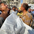 A group of men hold a body wrapped in a shroud. One of the men is weeping.