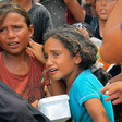 Girls with anguished faces hold pans
