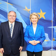 Israeli settler leader Dani Dayan stands beside European Commission President Ursula von der Leyen in front of a blue and yellow backdrop
