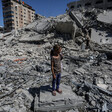 A girl wearing blue pants and a polka dot top stands on a massive pile of concrete rubble.