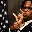 Congressman Wesley Bell gesticulates with an American flag near him