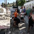 A boy holds a bucket beside other children and some adults next to a demolished building in occupied East Jerusalem 