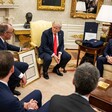 Germany's Chancellor Friedrich Merz holds a framed document as he sits beside US President Donald Trump and US Vice-President JD Vance 