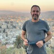 Smiling man seen against backdrop of Palestinian city