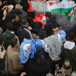 Crowds of mourners gather around the bodies of the Bani Odeh family, wrapped in shrouds, Palestine flags and keffiyehs