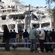 A crowd of people looks up at a partially collapsed apartment building