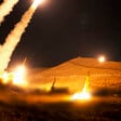 Several missiles launched at night trail smoke and fire