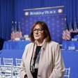 European Union Commissioner Dubravka Šuica stands in front of several US flags and a sign reading Board of Peace 