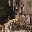 Group of men in helmets work in rubble