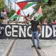 people stand behind large sign condemning genocide