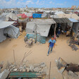 A boy stands in front of a group of tent shelters