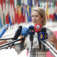European Union representative Kaja Kallas stretches out her arms as she stands behind several microphones of television channels 