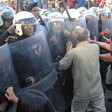 Protesters push at shields held by police wielding batons. 