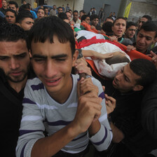 Young men carry body of slain man in funeral procession.