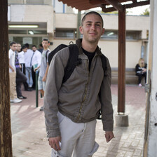 Smiling young man stands in front of building