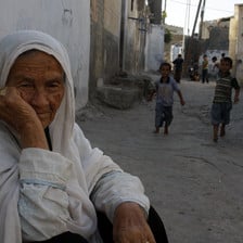 Elderly woman sits in refugee camp